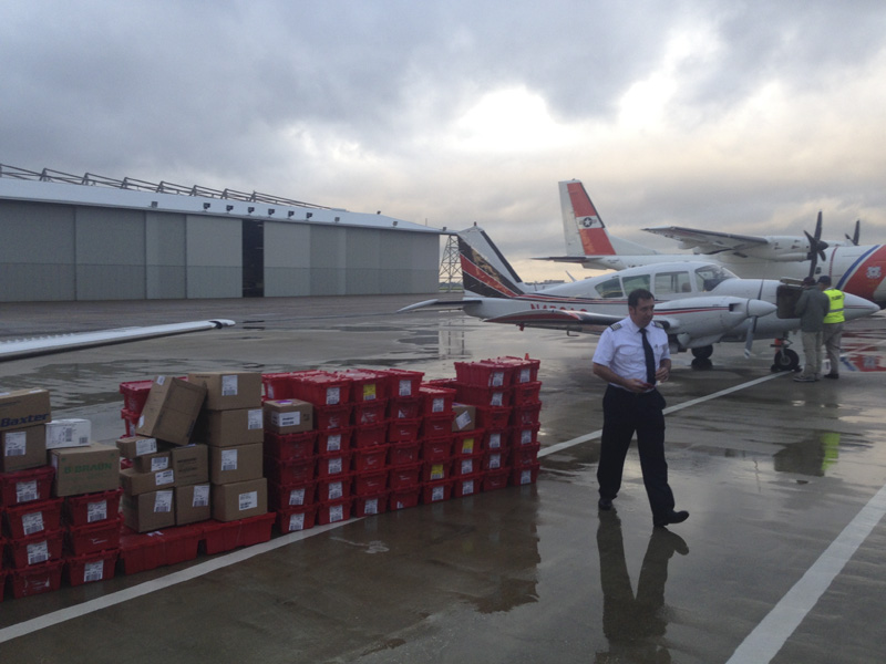 Pilot walks past cases and boxes on ramp