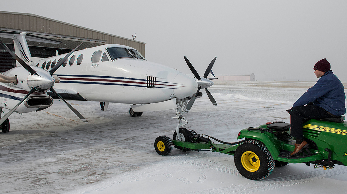 tug pulling single prop plane onto snowy ramp