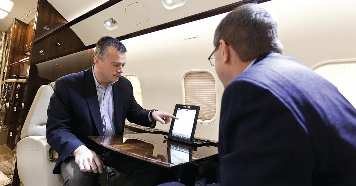 two men in air craft cabin with electronic notpad
